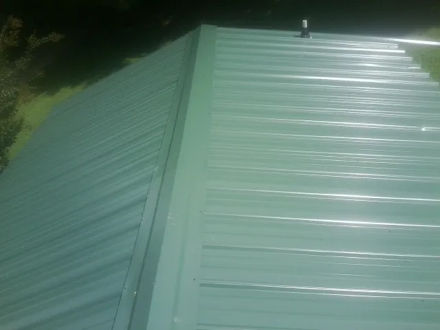 New green metal panels meeting at the ridge of a roof — Flat Roof Repair work by our crew in Picabo