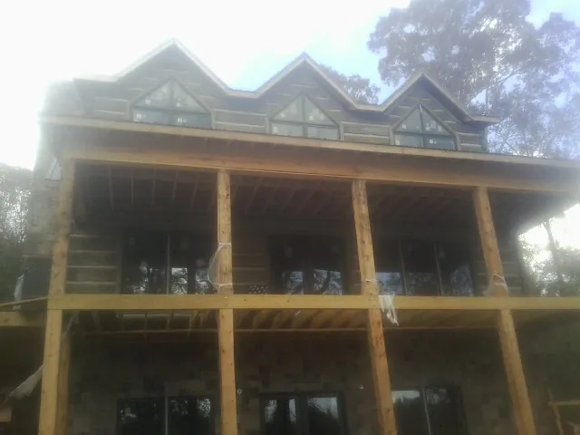 Dormers and porch framing on a large log home under construction — Roof Coating work by our crew in Picabo