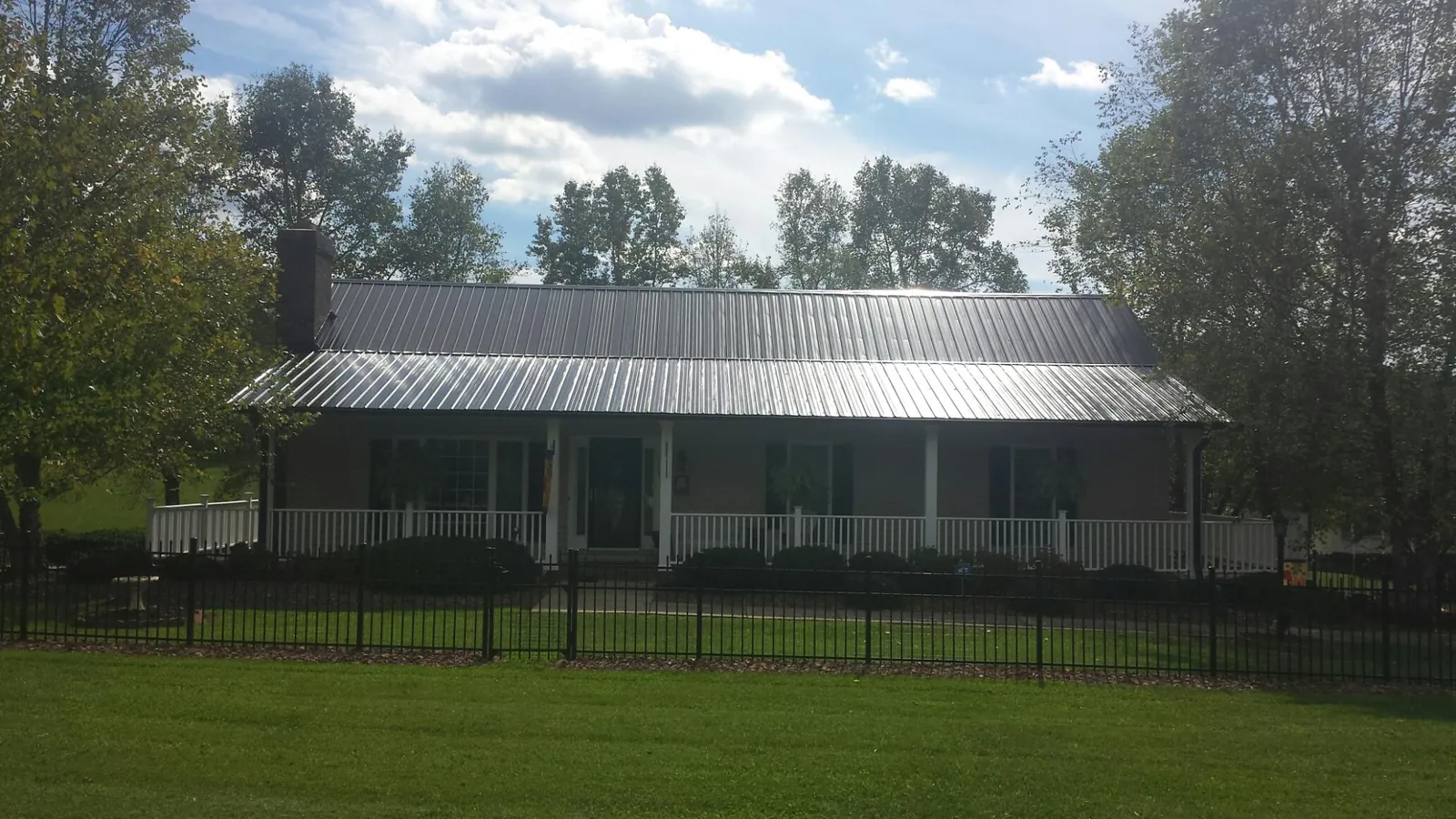 Gray metal roof on a brick ranch with a full width front porch — Gutter Guard Installation work by our crew in Picabo