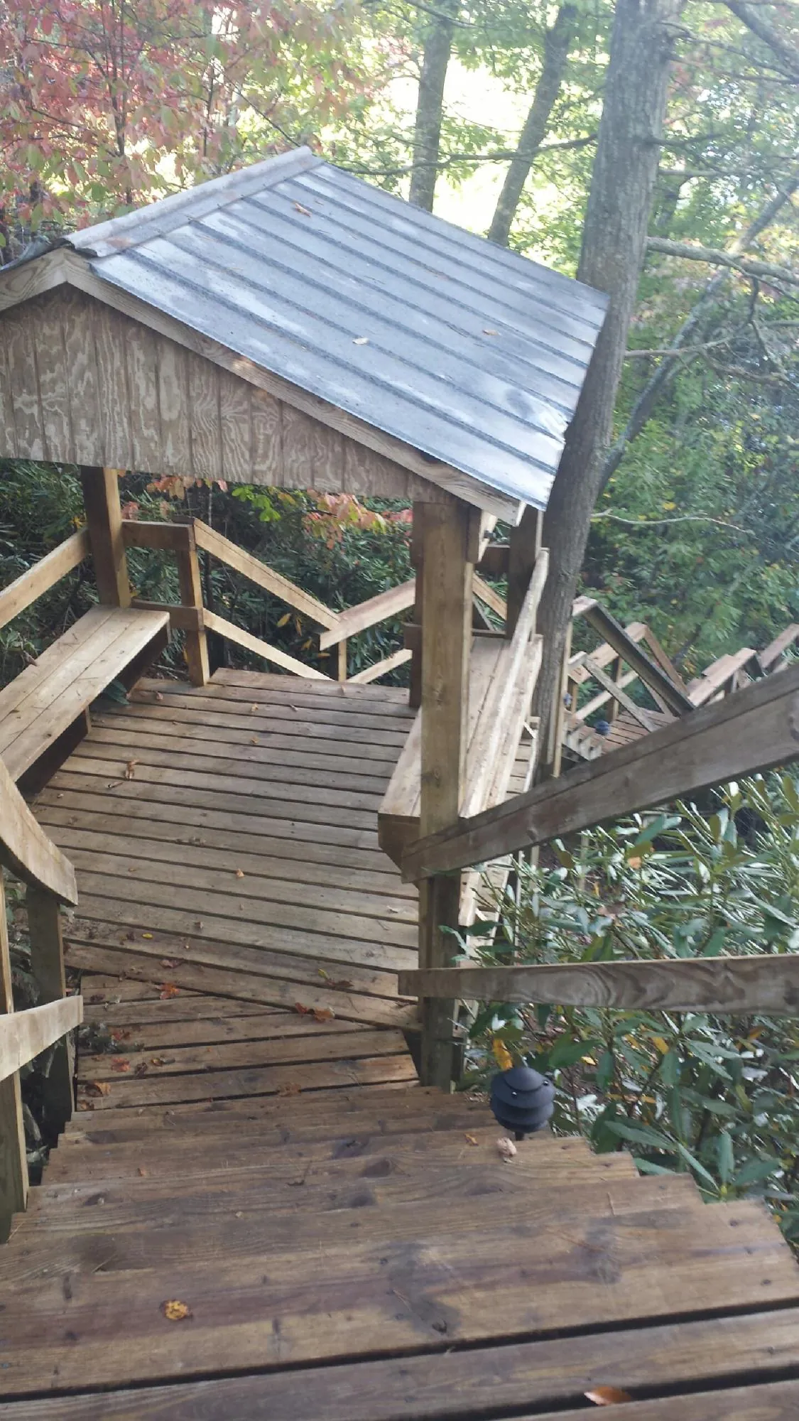 Metal roofed shelter over wooden steps on a wooded walkway — Skylight Repair & Installation work by our crew in Picabo